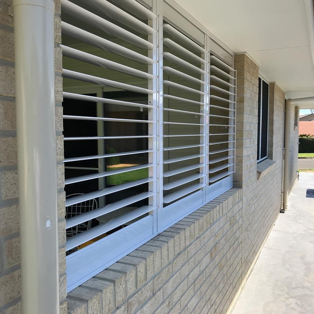 White Louvered Shutters on a Brick Building's Window — BlindDESIGN in Byron Bay, NSW