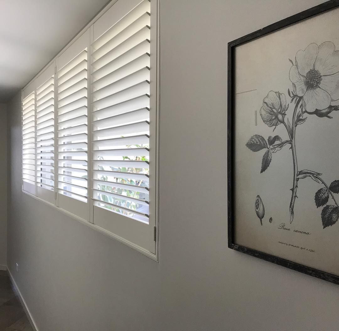 White Shutters on A Window Next to A Framed Floral Print — BlindDESIGN in Byron Bay, NSW