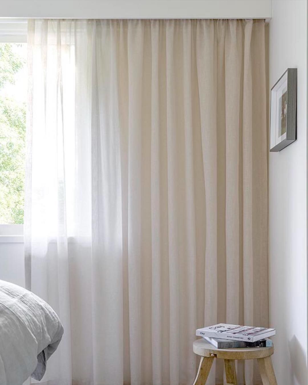 Light Beige Sheer Curtains Cover a Window Next to a White Wall With a Framed Art Piece — BlindDESIGN in Byron Bay, NSW