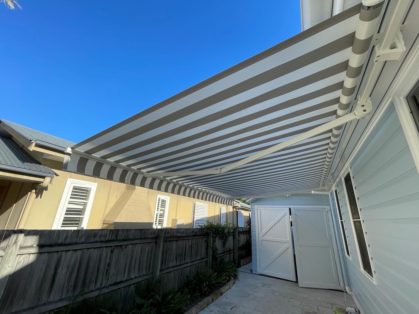 Striped Awning Extending from A Light Blue Building — BlindDESIGN in Lismore, NSW