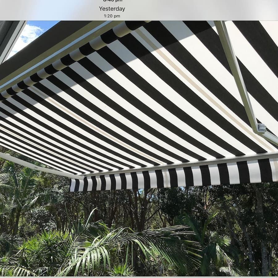 Black and White Striped Awning Shading a View of Lush Green Foliage — BlindDESIGN in Mullumbimby, NSW