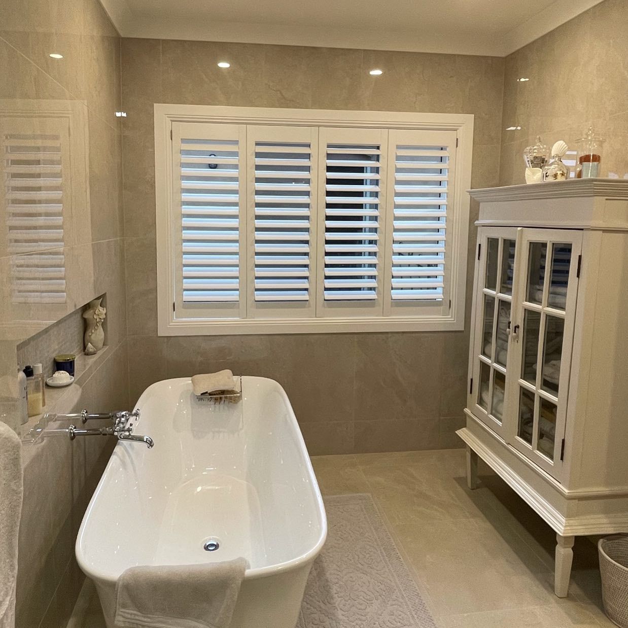 Bathroom With White Shutters, Freestanding Tub, White Cabinet, Beige Tile Walls — BlindDESIGN in Byron Bay, NSW