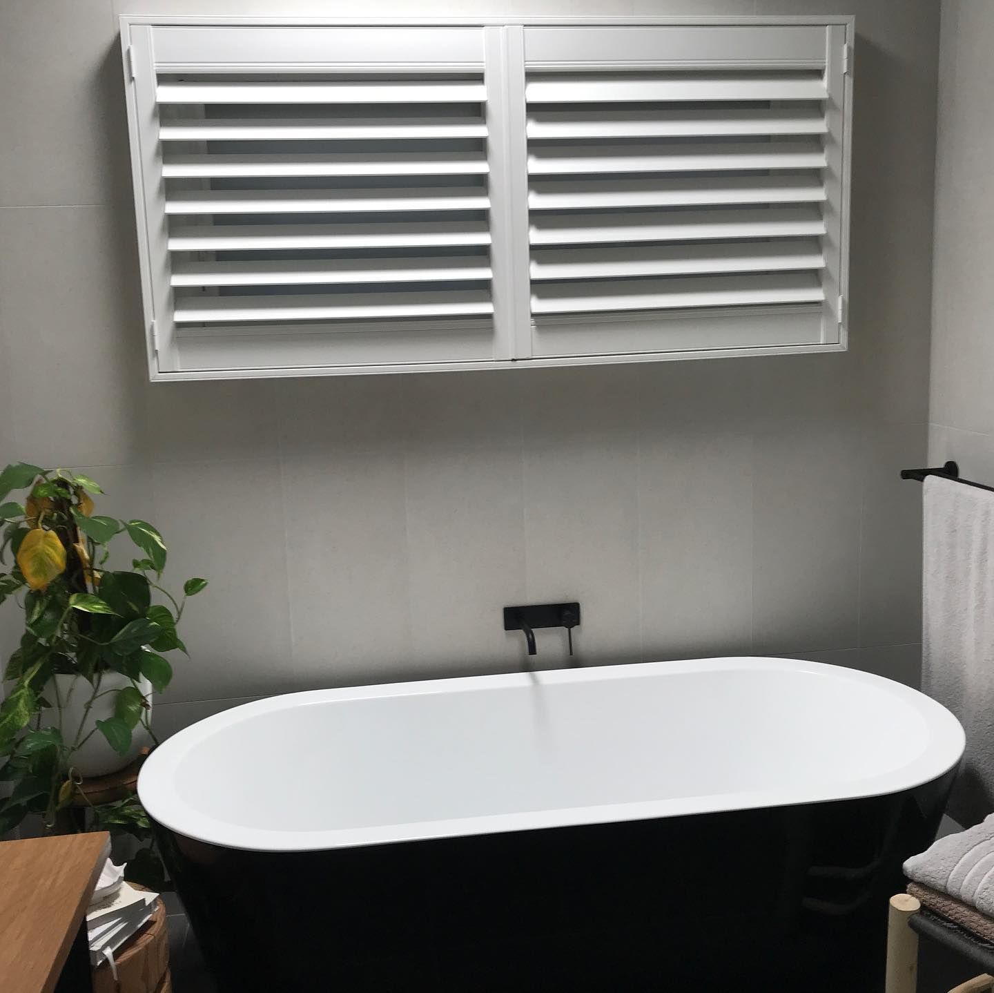A Modern Bathroom With a Black Bathtub, White Shutters, and a Potted Plant — BlindDESIGN in Tweed Heads, NSW