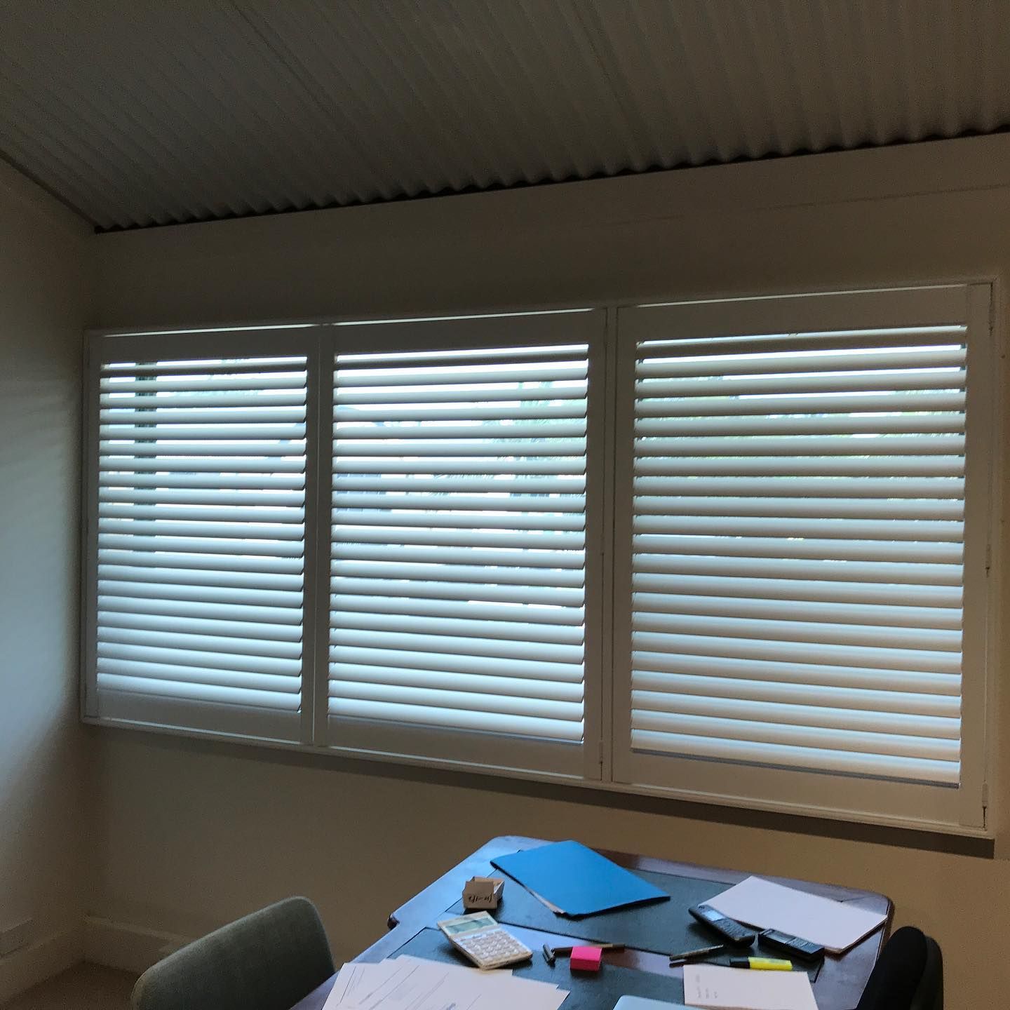 Three White Shuttered Windows Above a Desk in a Room — BlindDESIGN in Byron Bay, NSW