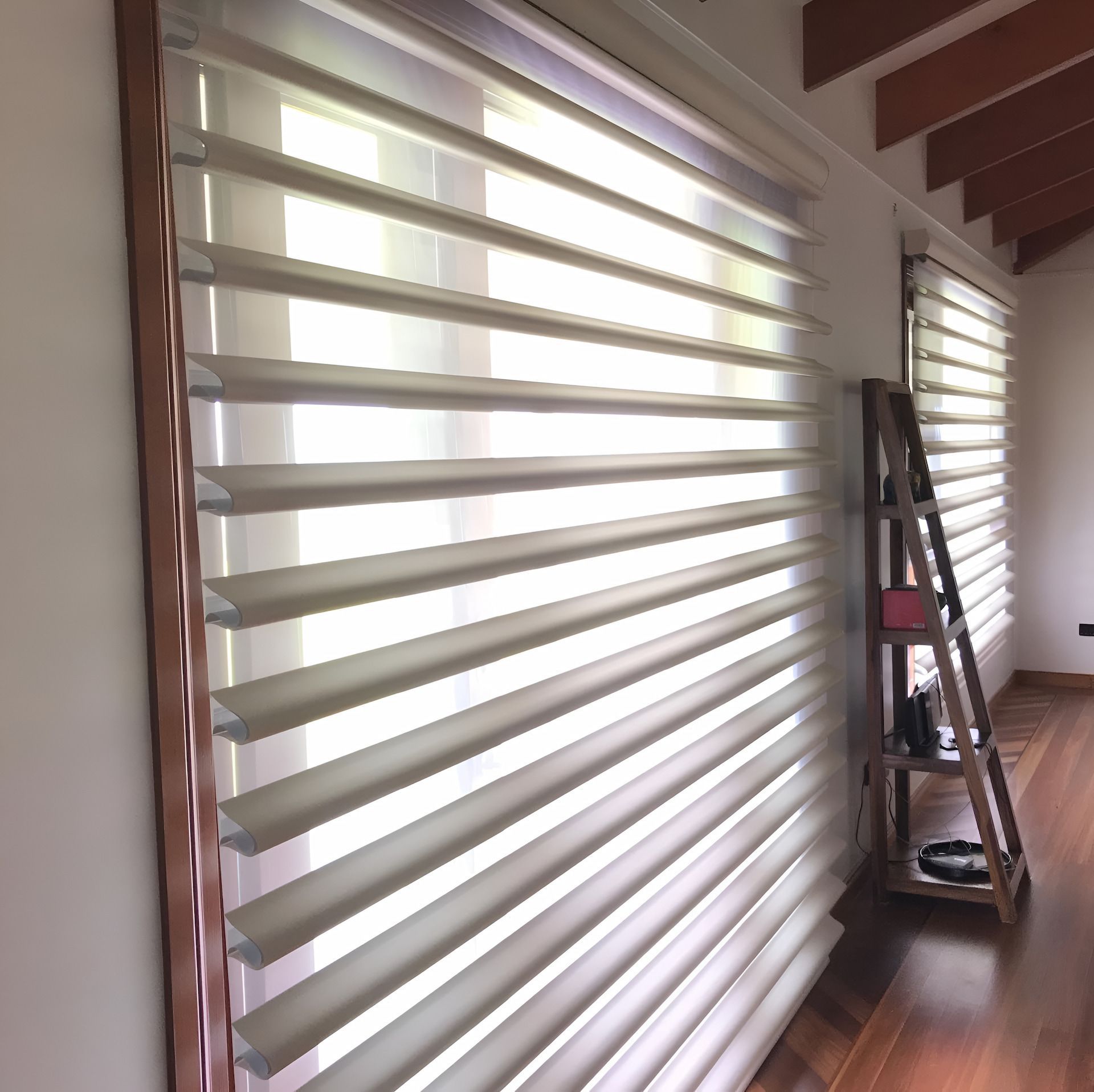 Beige and White Layered Window Blinds in a Room With a Wooden Ladder and Hardwood Floors — BlindDESIGN in Byron Bay, NSW
