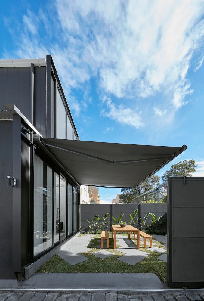 Modern Outdoor Patio With Black Awning, Dining Table, and Plants Under a Blue Sky — BlindDESIGN in Mullumbimby, NSW