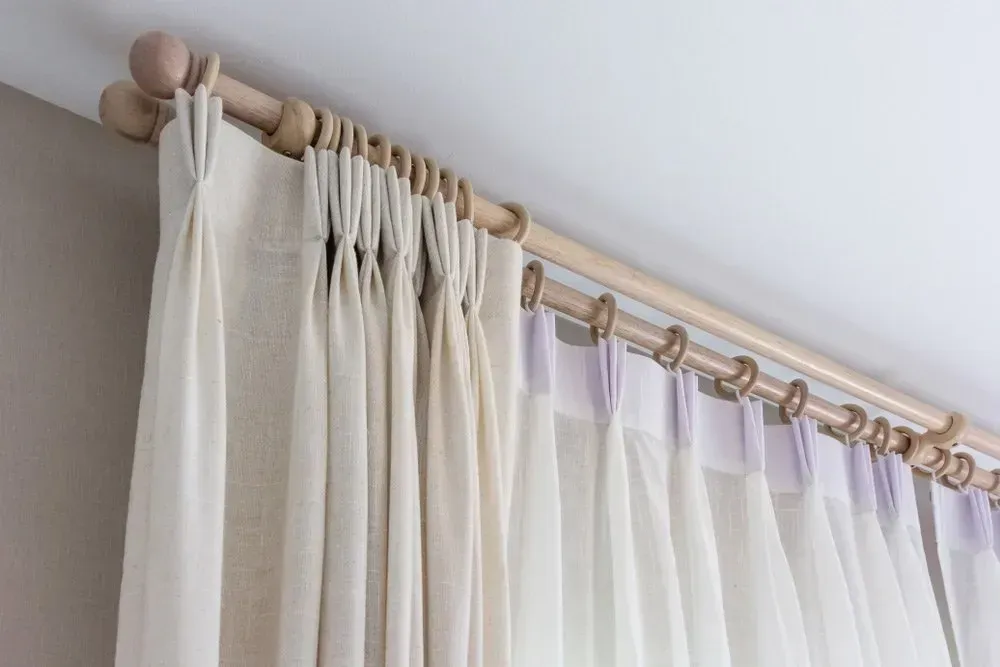 Beige Curtains Hanging From a Double Wooden Rod, Set Against a White Ceiling and Beige Wall — BlindDESIGN in Byron Bay, NSW