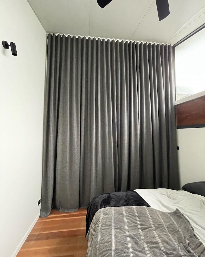 Gray Curtains Cover A Wall In A Bedroom — BlindDESIGN in Byron Bay, NSW