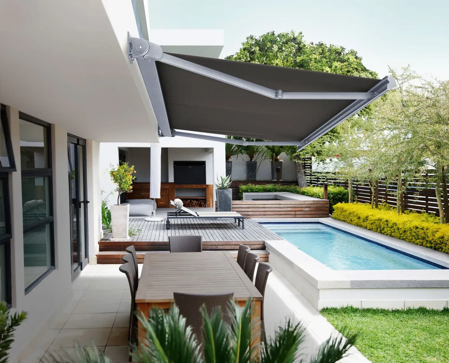 Patio With Retractable Gray Awning, Pool, Dining Table, and Lounge Area — BlindDESIGN in Byron Bay, NSW