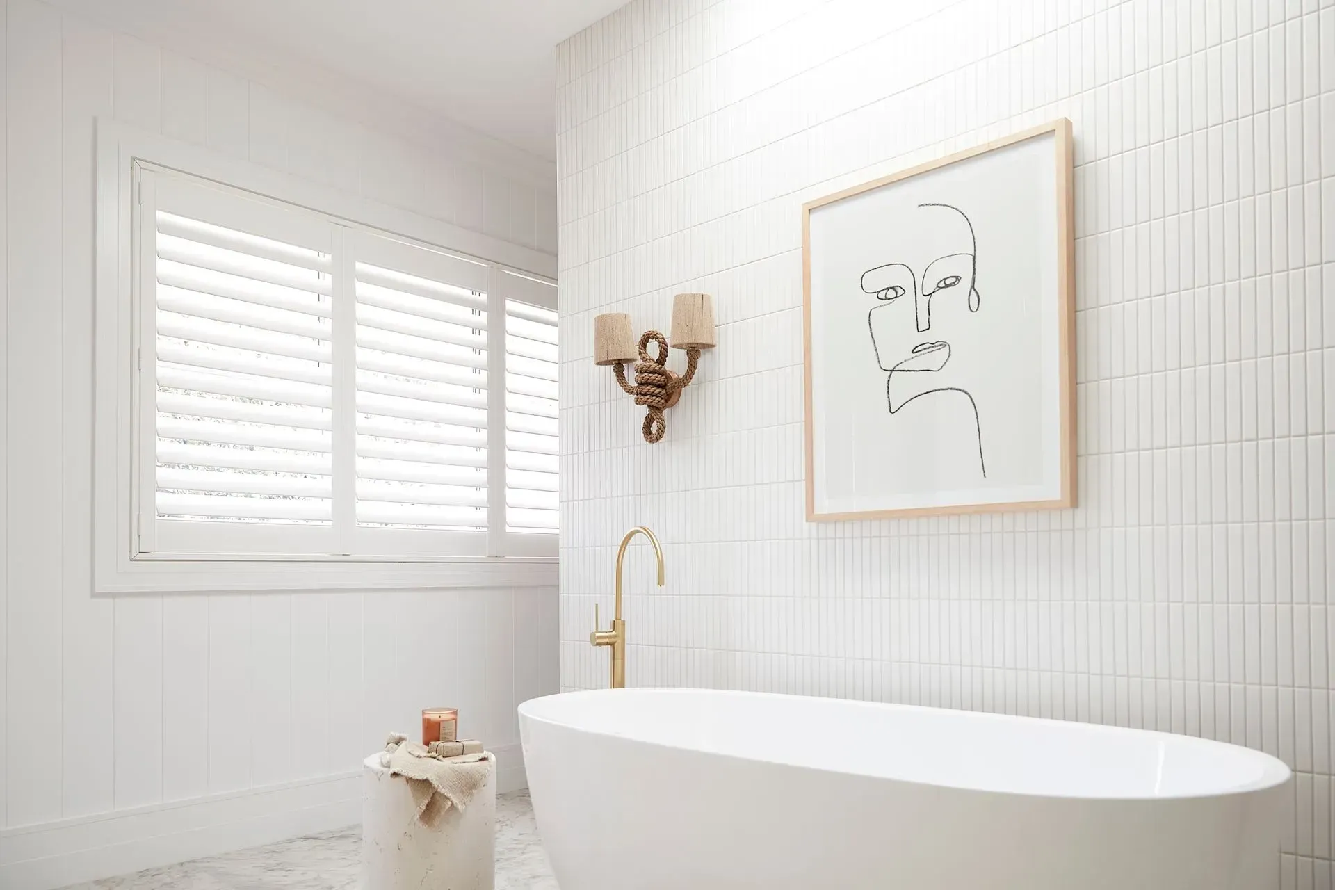 White Bathroom With Tub, Art, Sconce, and Window With Shutters — BlindDESIGN in Byron Bay, NSW