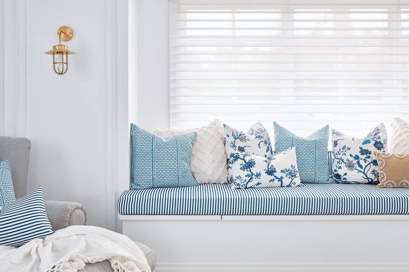 Window seat with blue and white patterned cushions, pillows, and a brass wall sconce — BlindDESIGN in Byron Bay, NSW