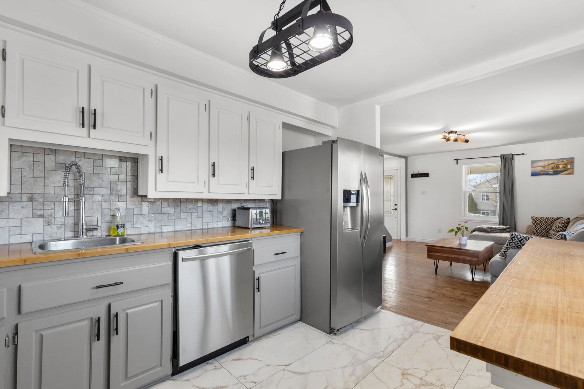 Cuisine grise avec électroménagers en acier inoxydable, comptoir en bois massif et crédence en pierre.