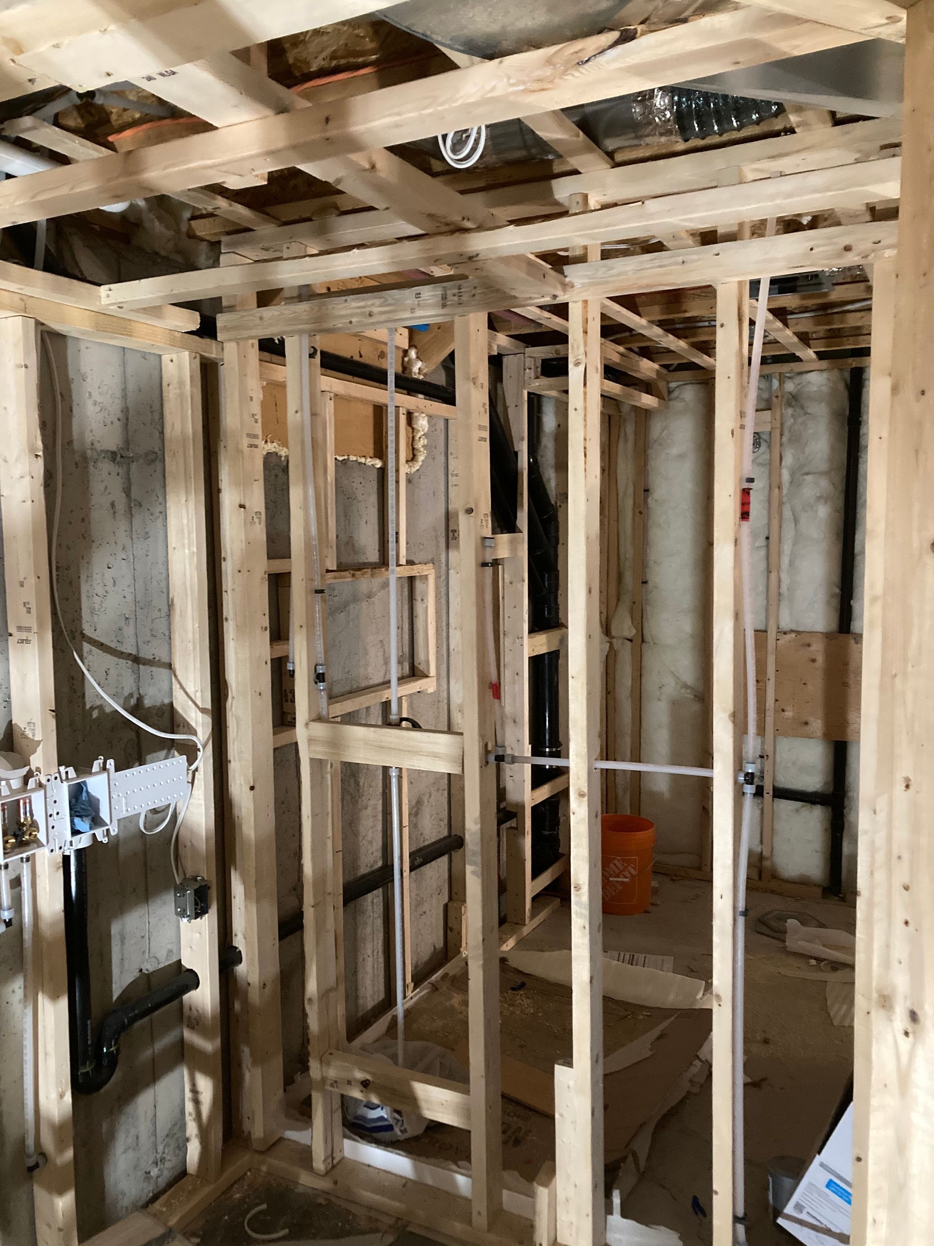 Vue intérieure d'une construction à ossature bois. Les murs à montants et les solives de plafond délimitent une pièce.