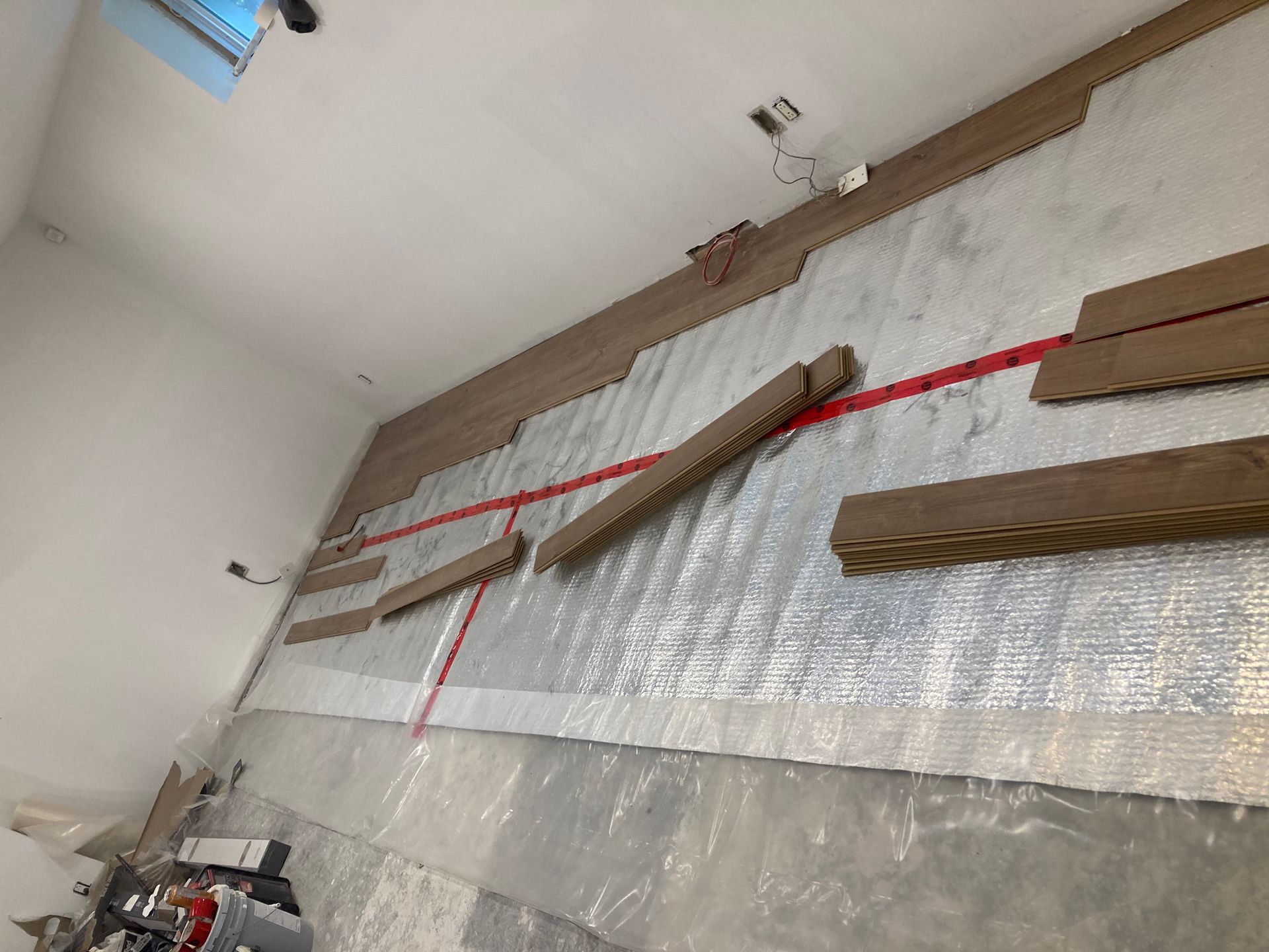 Des lames de parquet sont posées sur un isolant réfléchissant, laissant apparaître les tubes rouges. À l'intérieur.