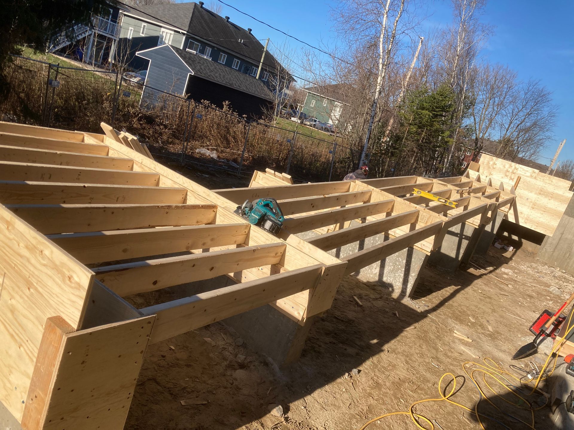 Construction d'une structure de terrasse en bois sur un terrain en pente. La lumière du soleil illumine la structure.
