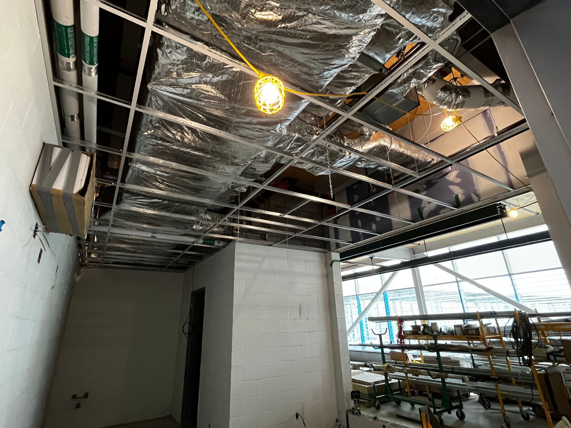 Intérieur du chantier : faux plafond, conduits de ventilation, tuyaux apparents et isolation.