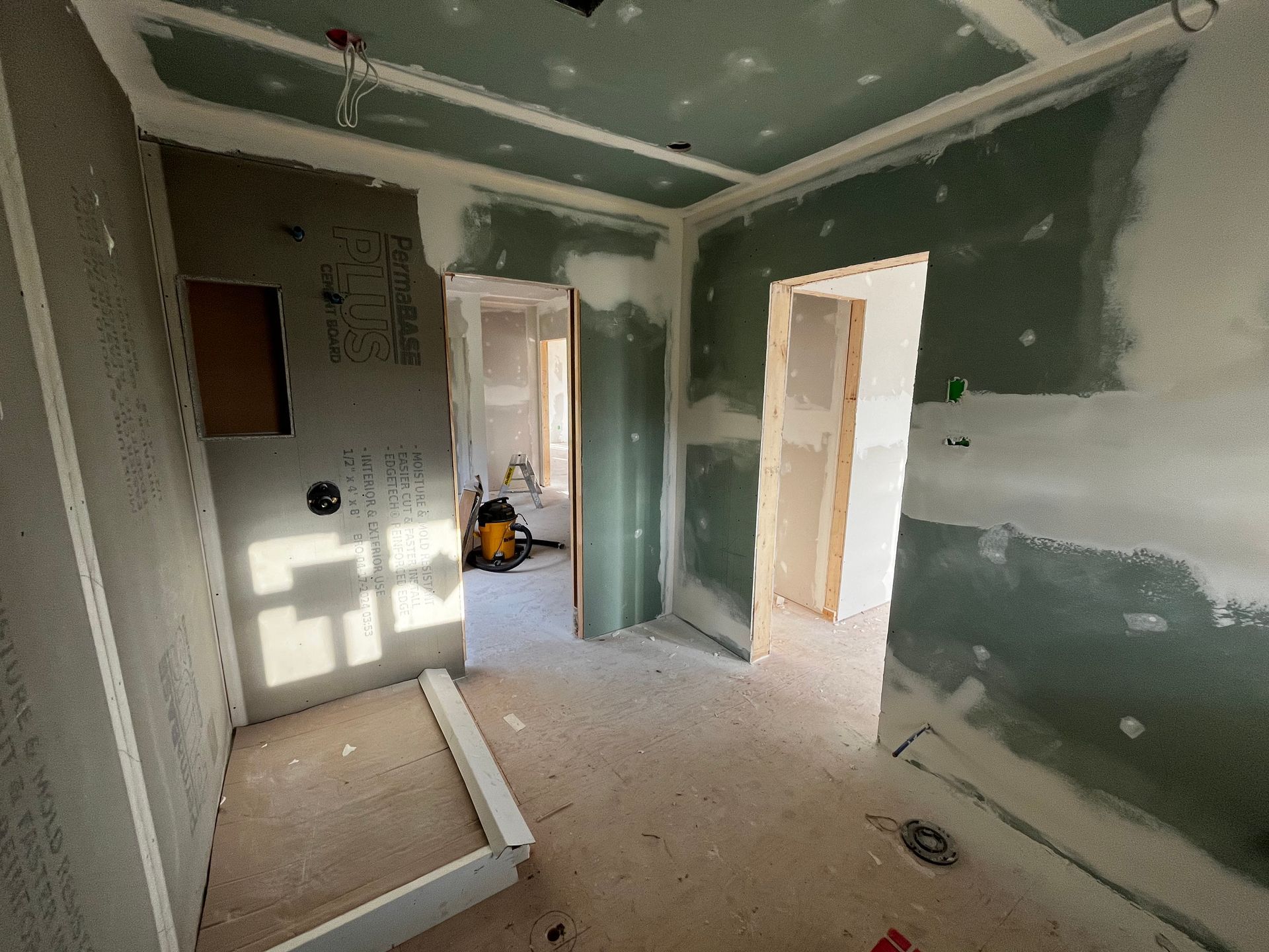 Aménagement intérieur d'une pièce : cloisons sèches vertes, portes ouvertes, finitions inachevées.