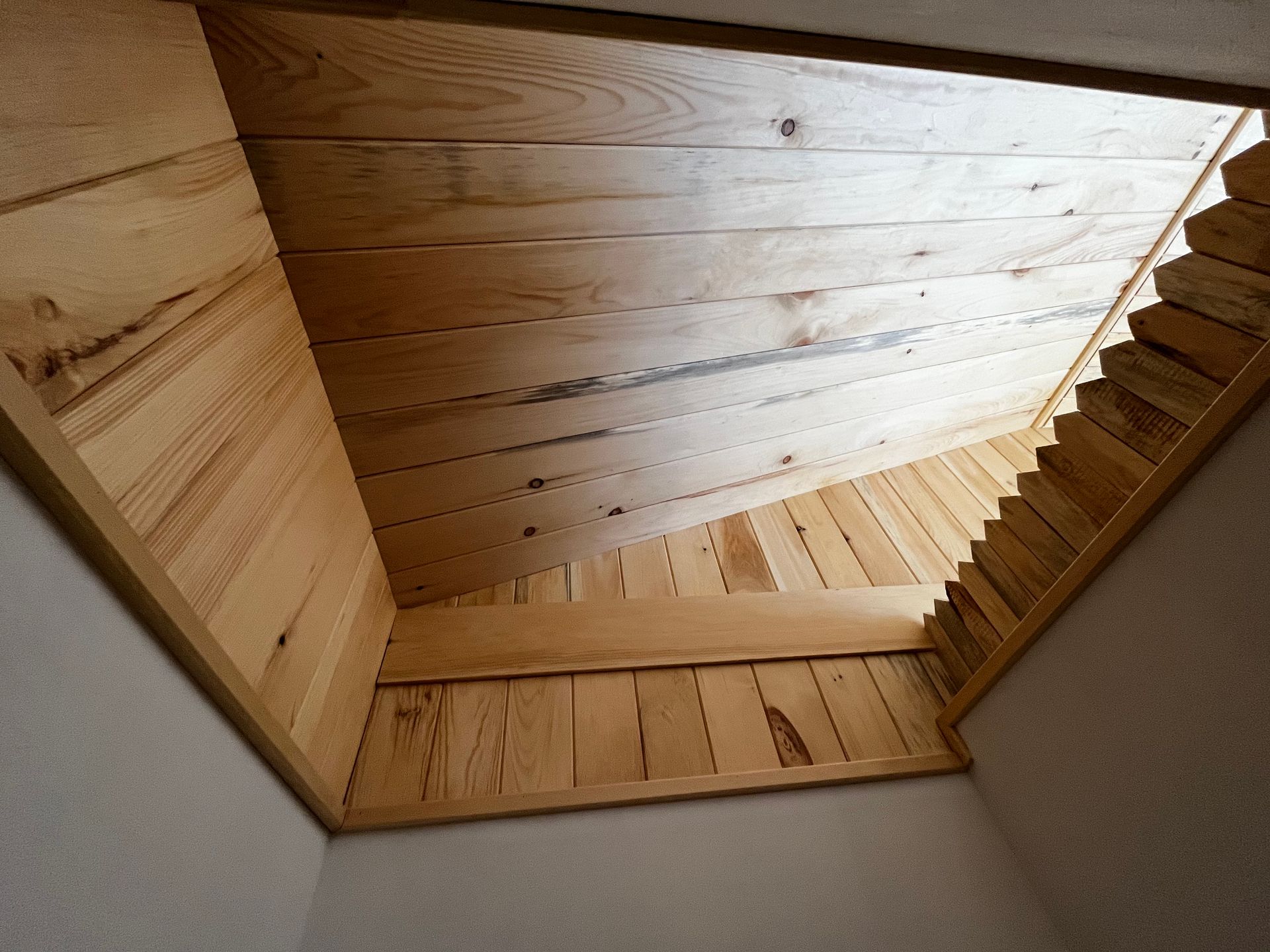 Intérieur avec puits de lumière en bois, panneaux et moulures en bois inclinés.
