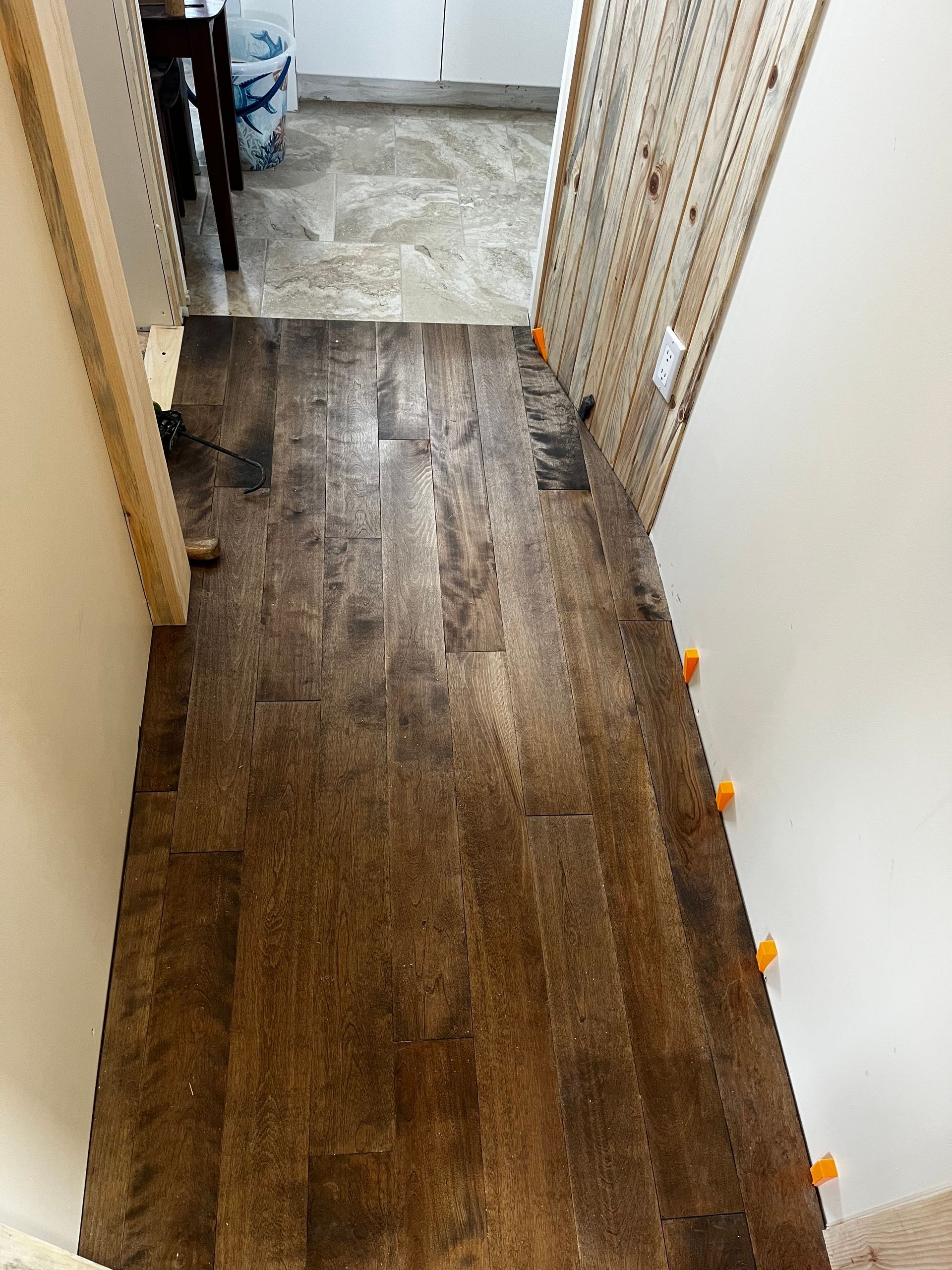 Couloir avec parquet en bois et entretoises orange.