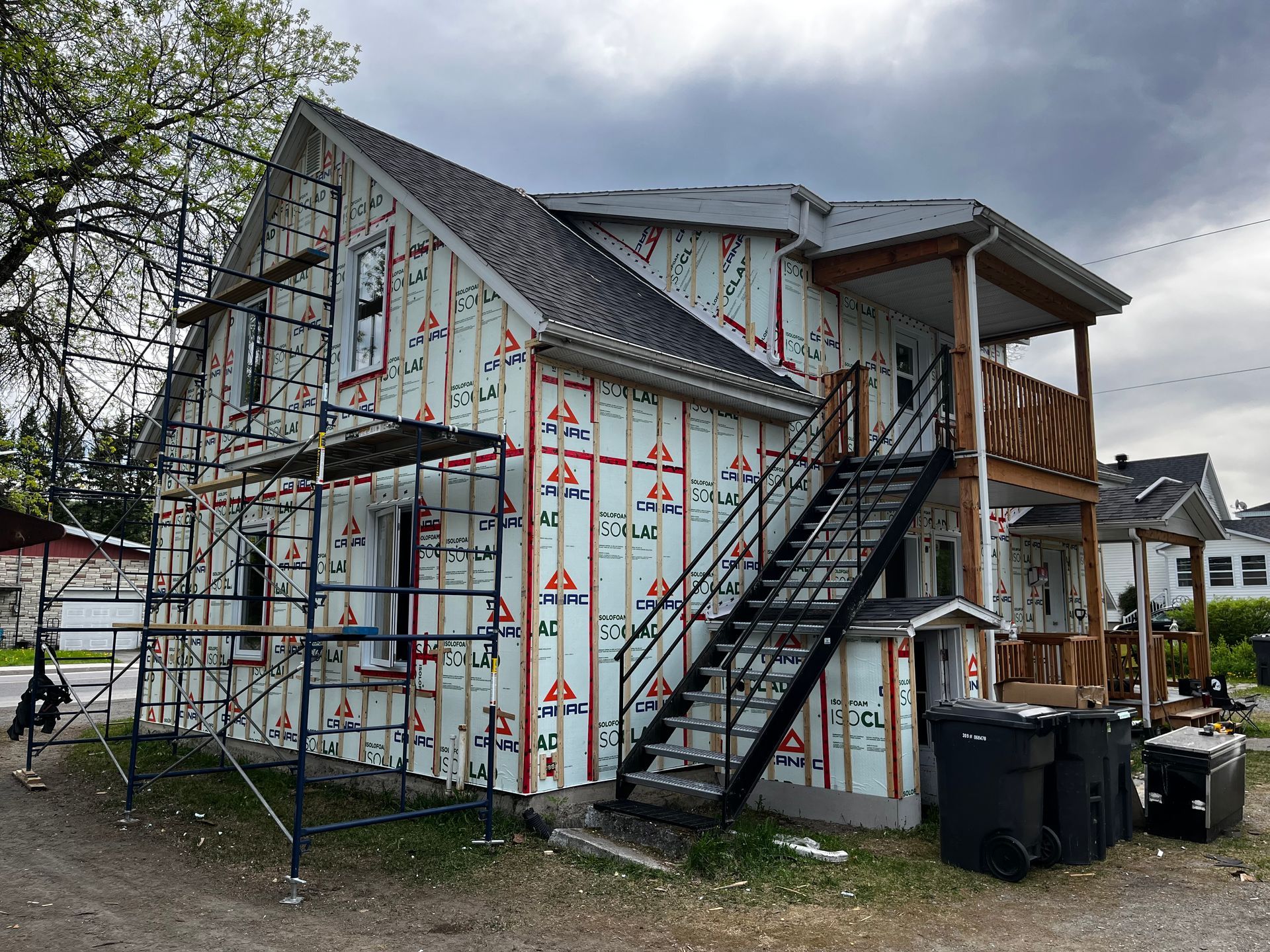 Extérieur du bâtiment en construction avec échafaudages et escalier métallique.