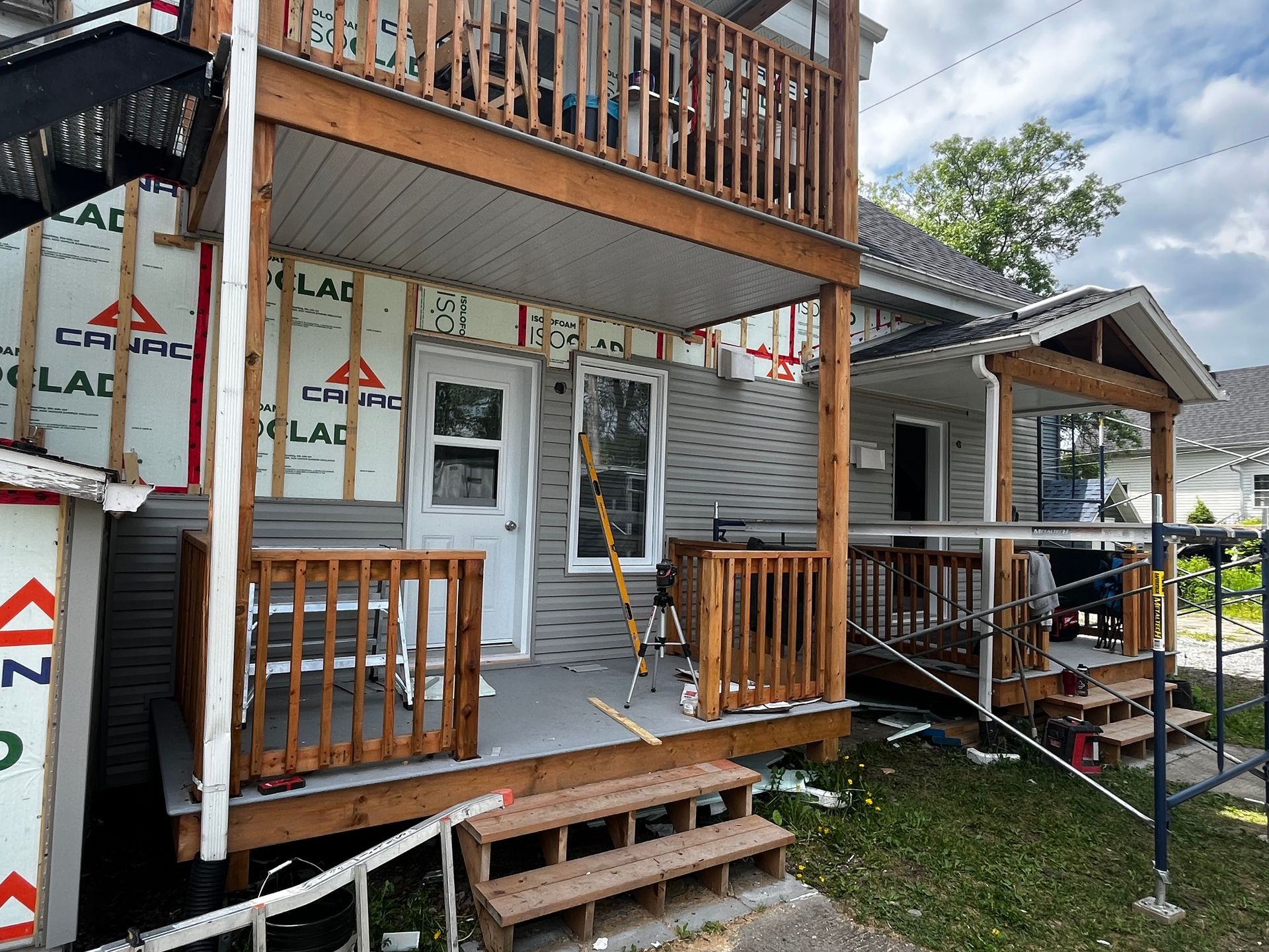 Extérieur de la maison en cours de rénovation : terrasse à deux étages, échafaudages, murs apparents.