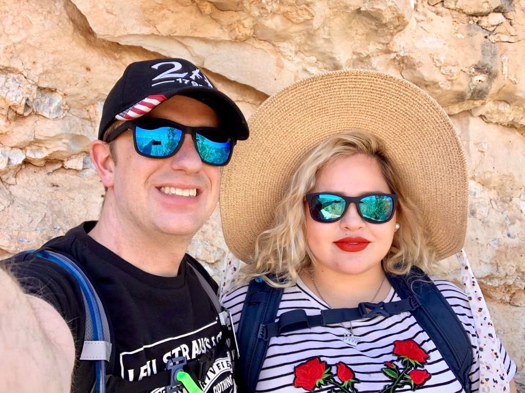Un hombre y una mujer con gafas de sol y sombreros posan para una fotografía.