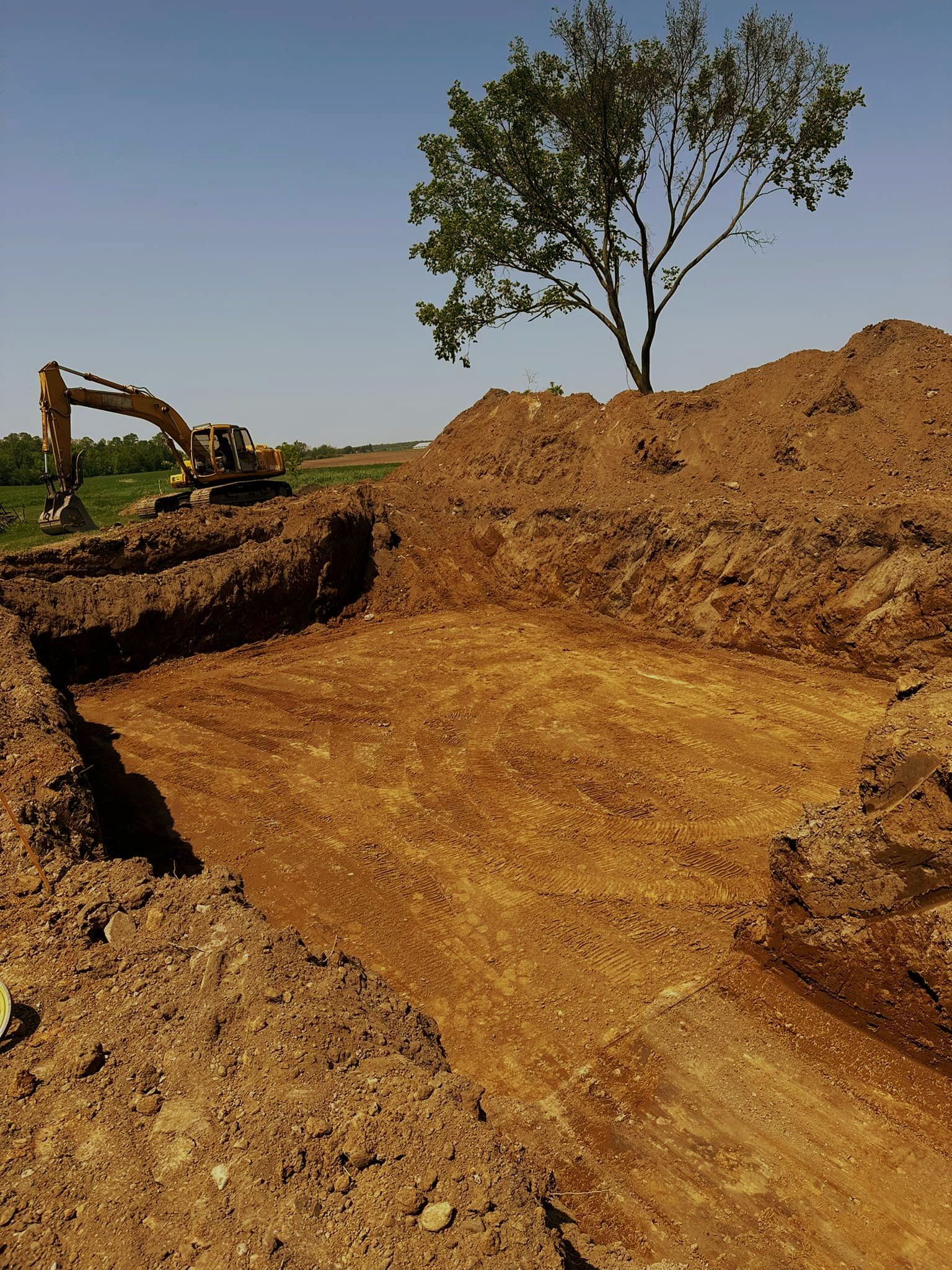 A large pile of dirt with a tree in the background