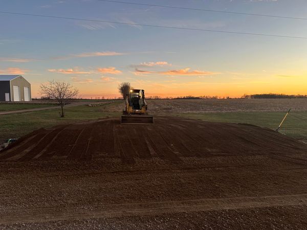 A bulldozer is working on a dirt road at sunset.