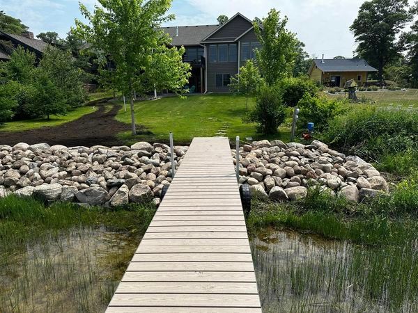 A wooden dock leading to a house on a lake