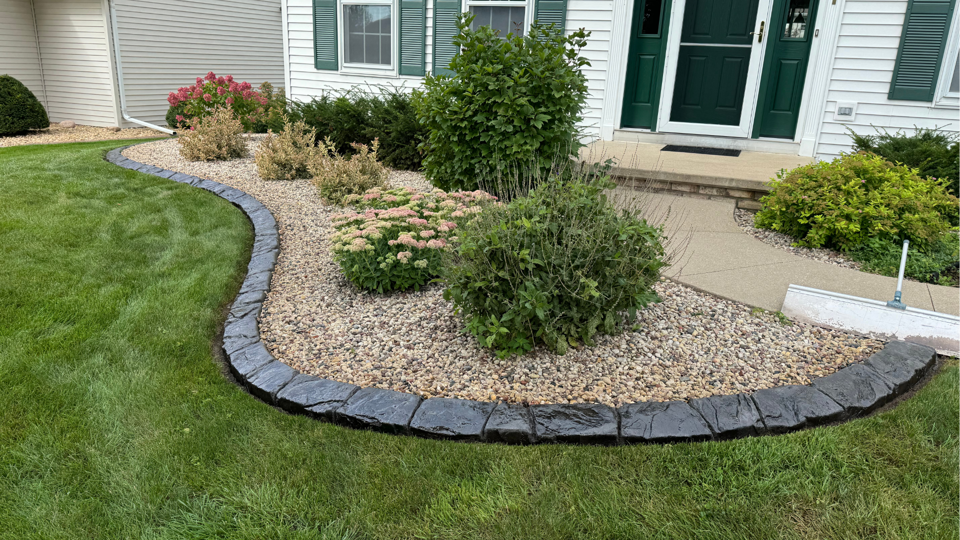A lawn with a concrete curb and a walkway in front of a house.