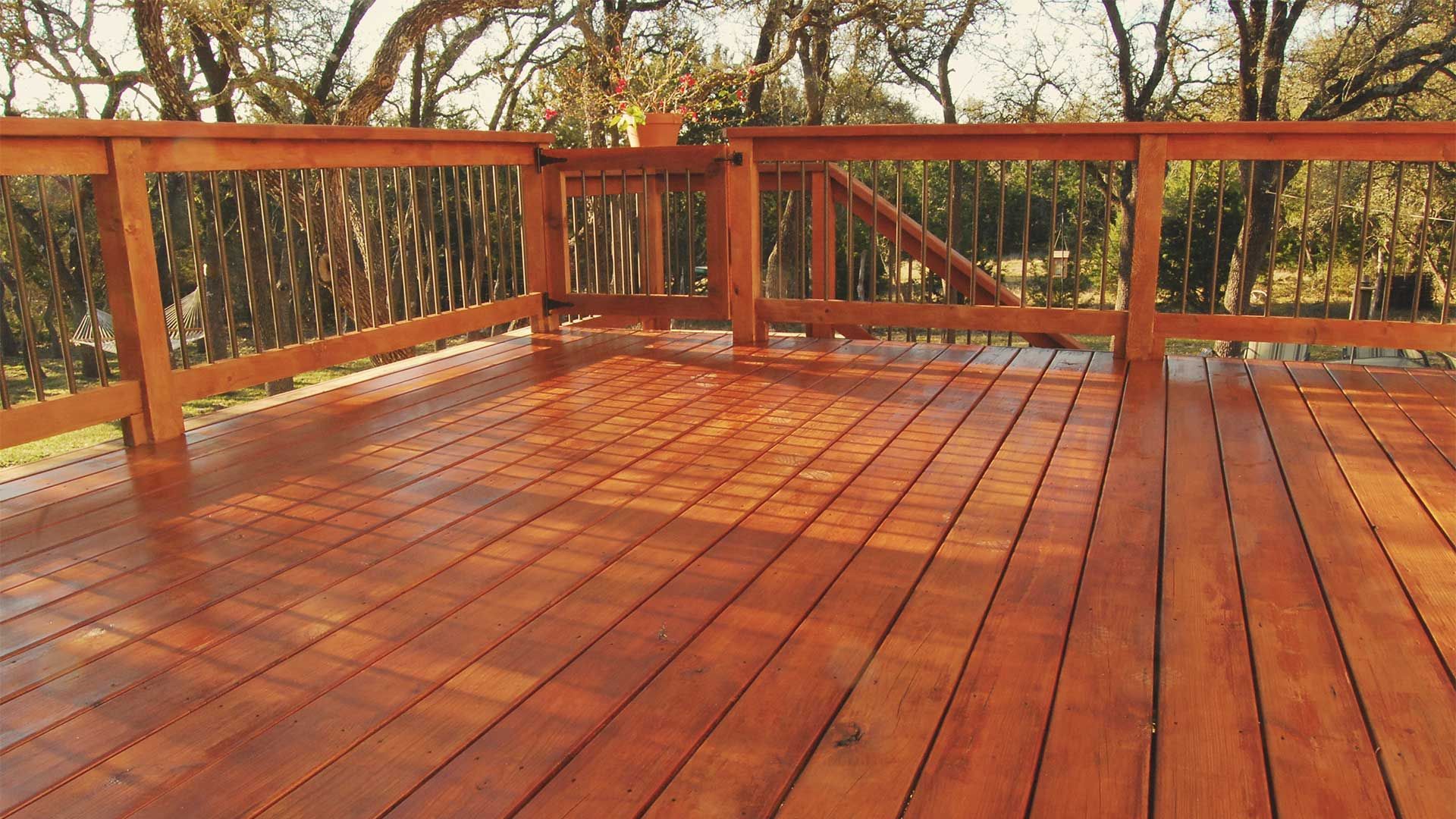 A wooden deck with a railing and trees in the background