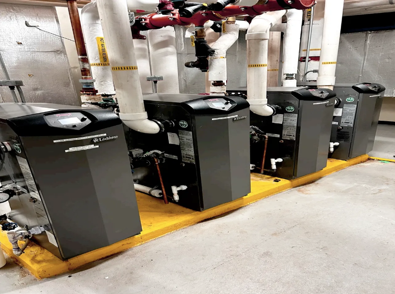 A row of boilers are lined up in a room.