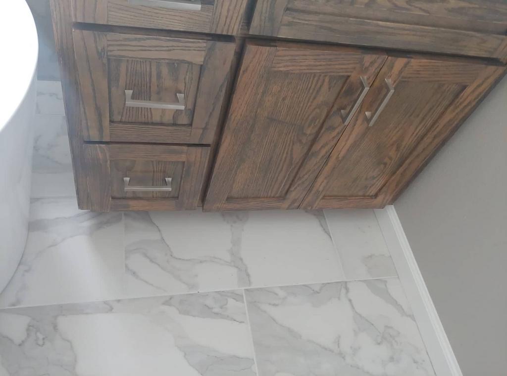 A bathroom vanity with wooden cabinets and marble tile floors.