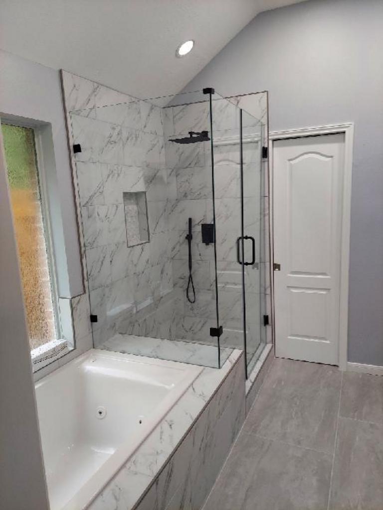 A bathroom with a tub and a shower with a glass door.
