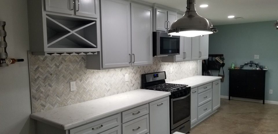 A kitchen with white cabinets , a stove , a microwave , and a wine rack.