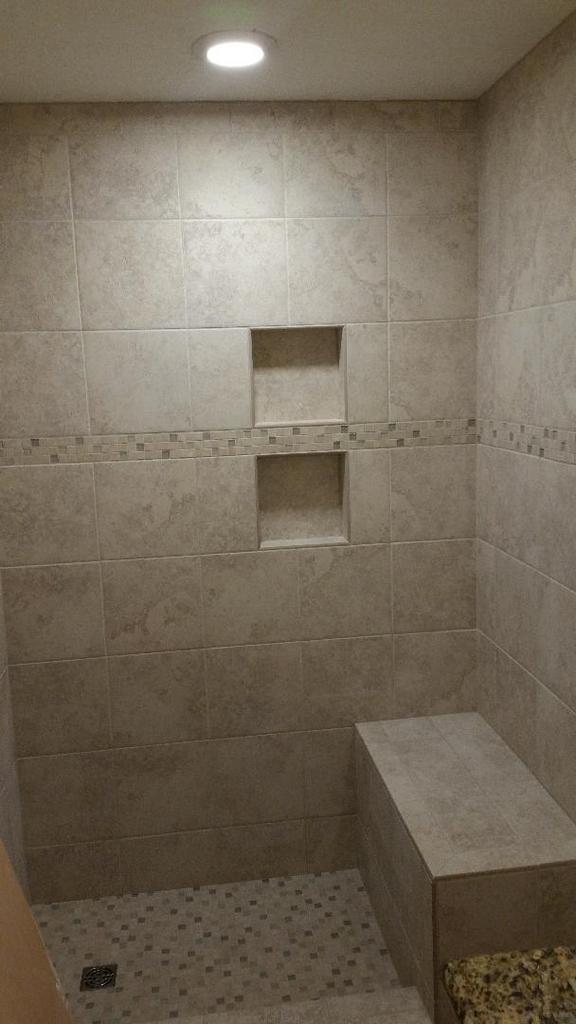 A shower with a bench and shelves in the wall.
