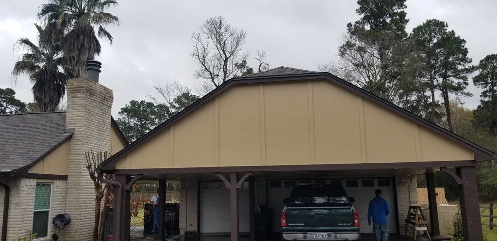 A truck is parked under a carport in front of a house.
