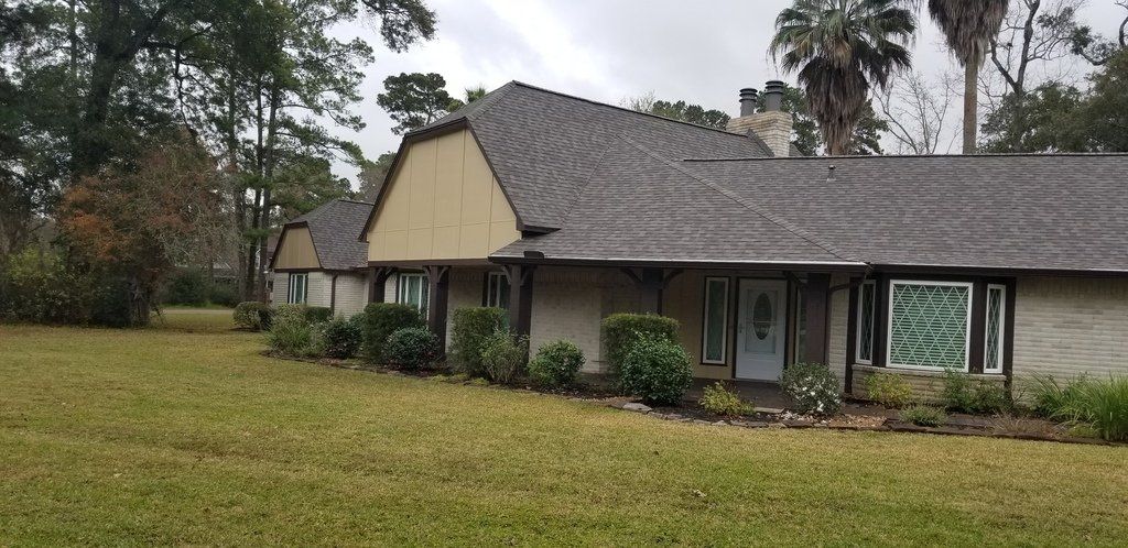 A large house with a gray roof is sitting on top of a lush green field.