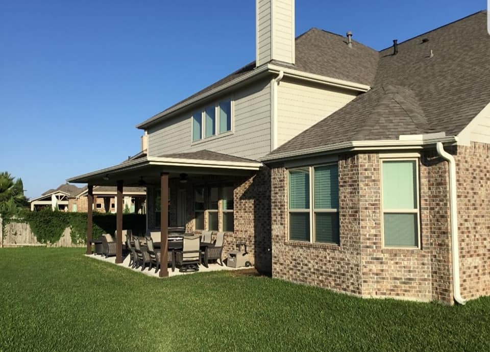 A large brick house with a covered patio in front of it