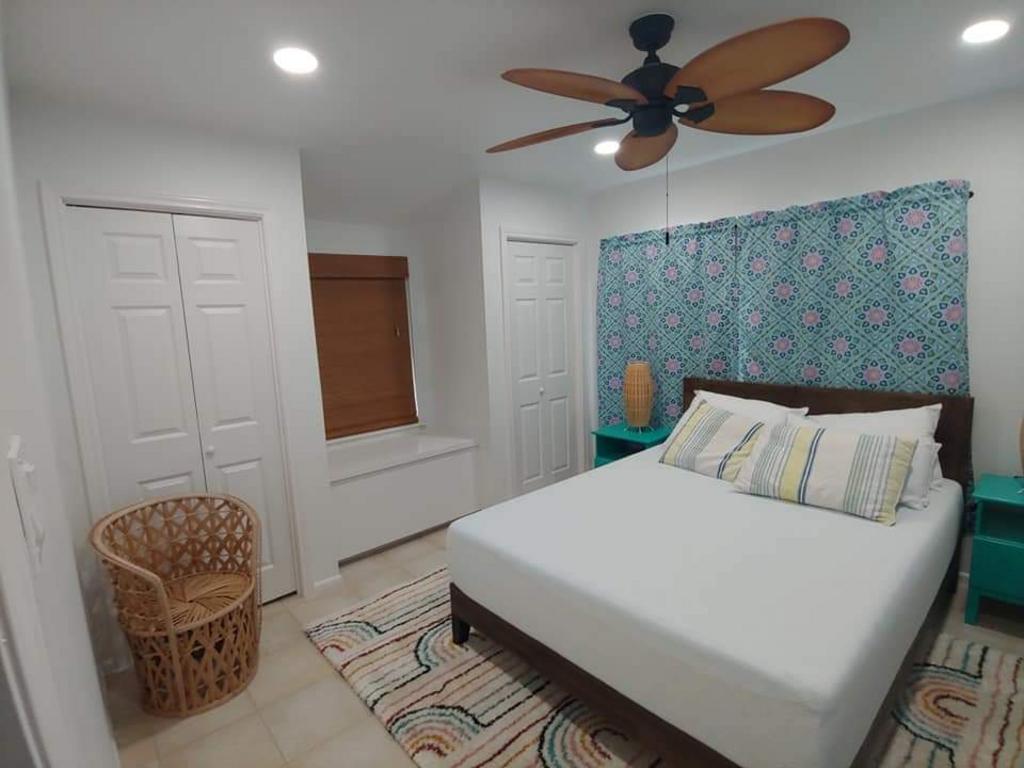 A bedroom with a bed , chair , nightstand and ceiling fan.