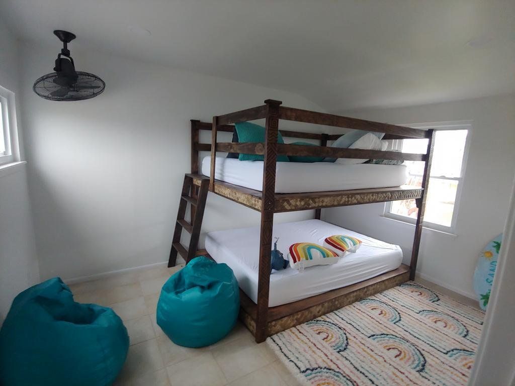 A bedroom with a bunk bed , bean bag chairs and a fan.