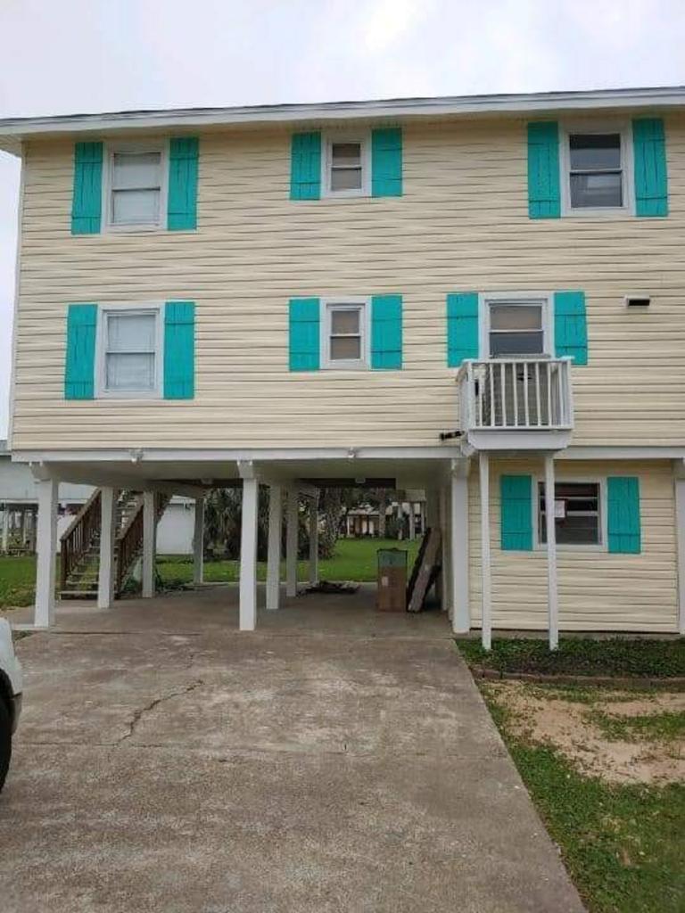 A house with blue shutters and a car parked in front of it.
