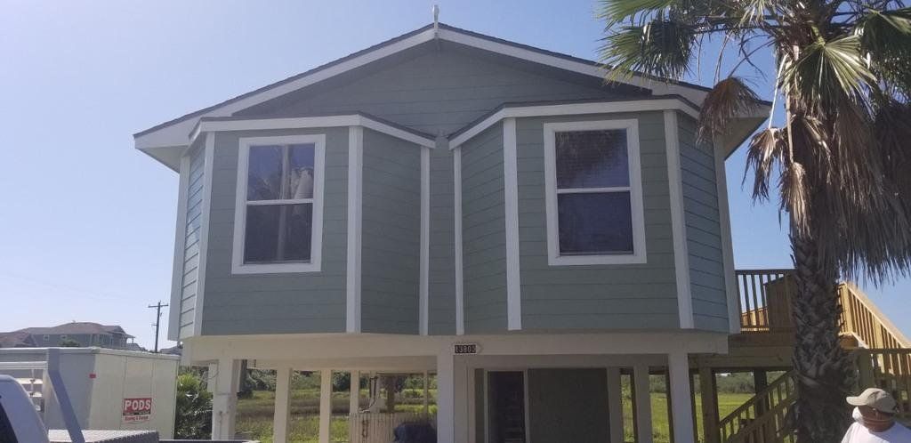 A man is standing in front of a house that is being built on stilts.