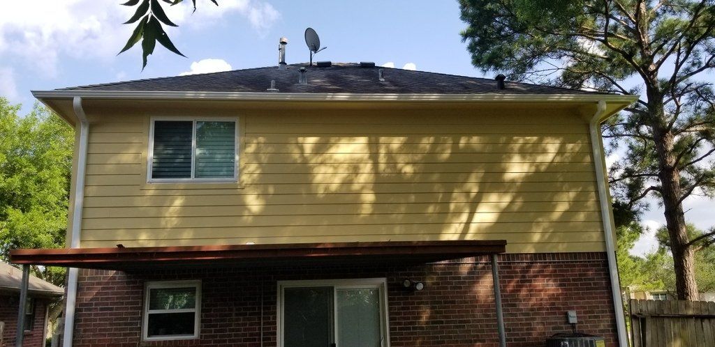 The back of a house with a satellite dish on the roof.