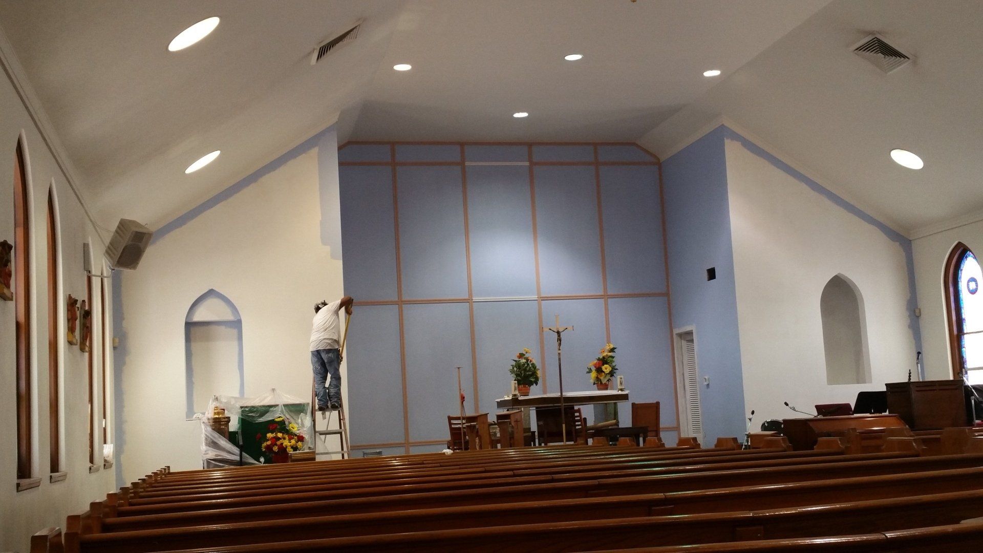 A church with rows of wooden pews and a blue wall