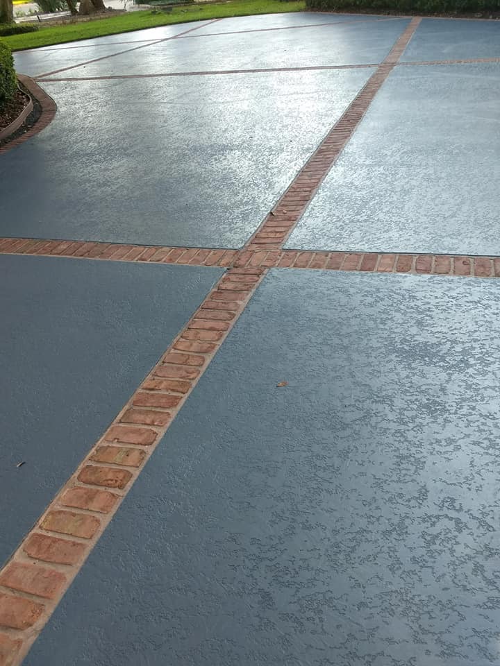 A blue concrete driveway with a brick border