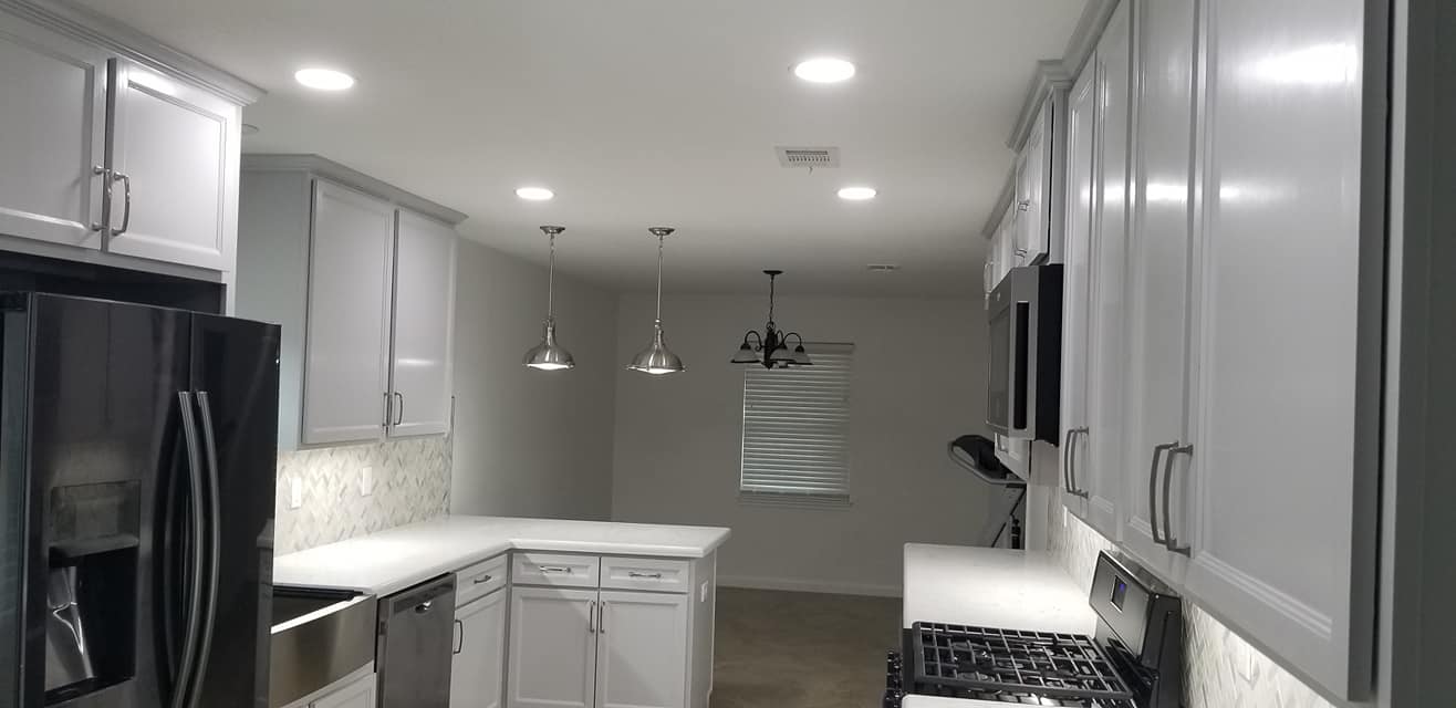A kitchen with white cabinets , stainless steel appliances , a refrigerator and a stove.