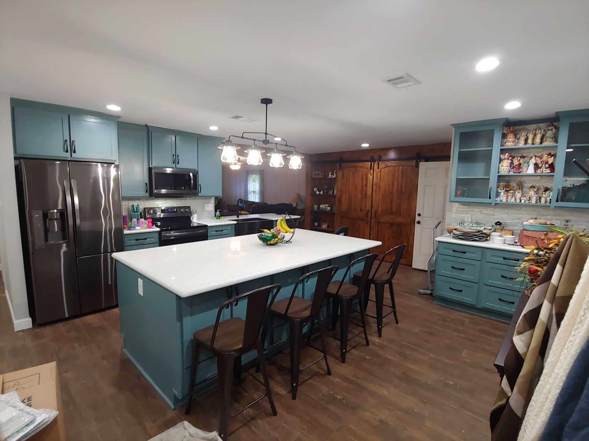 A kitchen with blue cabinets , stainless steel appliances , and a large island.
