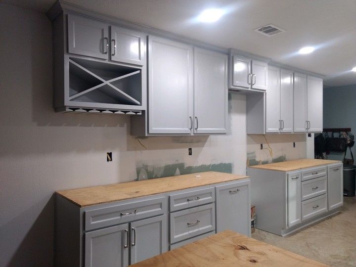 A kitchen with white cabinets and wooden counter tops