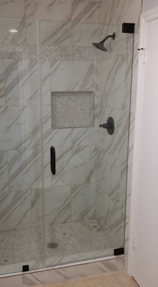 A shower stall with a glass door and a shower head in a bathroom.